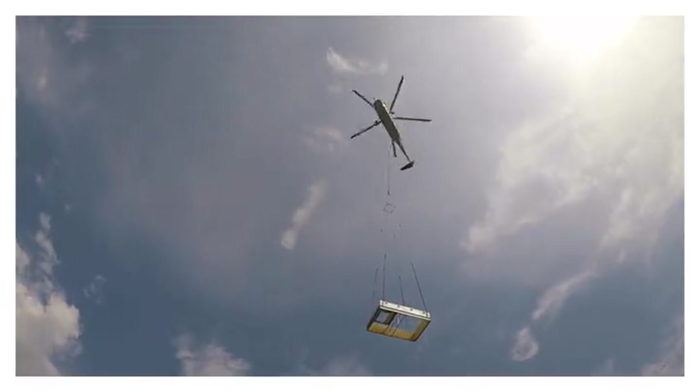 A helicopter lowering a rooftop HVAC unit onto an Aeromark job site